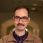 a smiling picture of Mustafa Aghahosseini, arms crossed